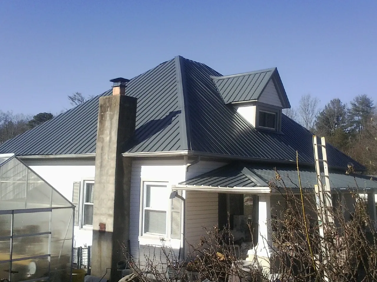Dark blue standing seam metal roof on a white farmhouse with dormer — Slate & Tile Roof Repair by Roofing Brothers in Ruckersville