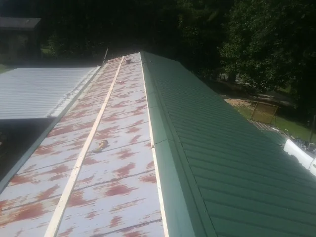 Old rusted panels beside newly installed green metal roofing — Wind Damage Roof Repair by Roofing Brothers in Ruckersville