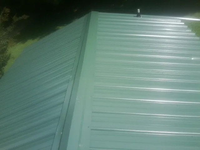New green metal panels meeting at the ridge of a roof — Flat Roof Repair work by our crew in Ruckersville