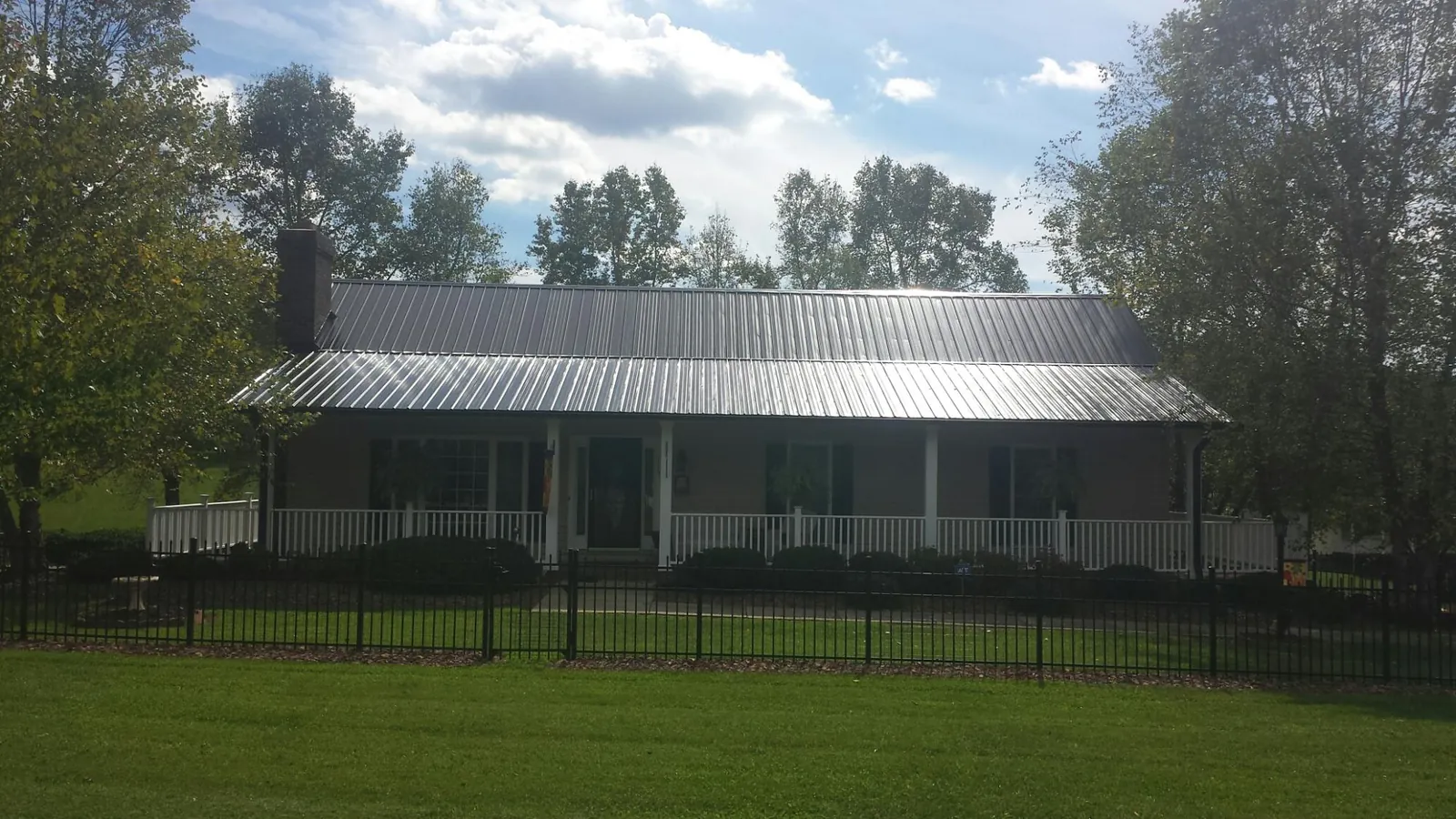 Gray metal roof on a brick ranch with a full width front porch — Gutter Guard Installation work by our crew in Ruckersville