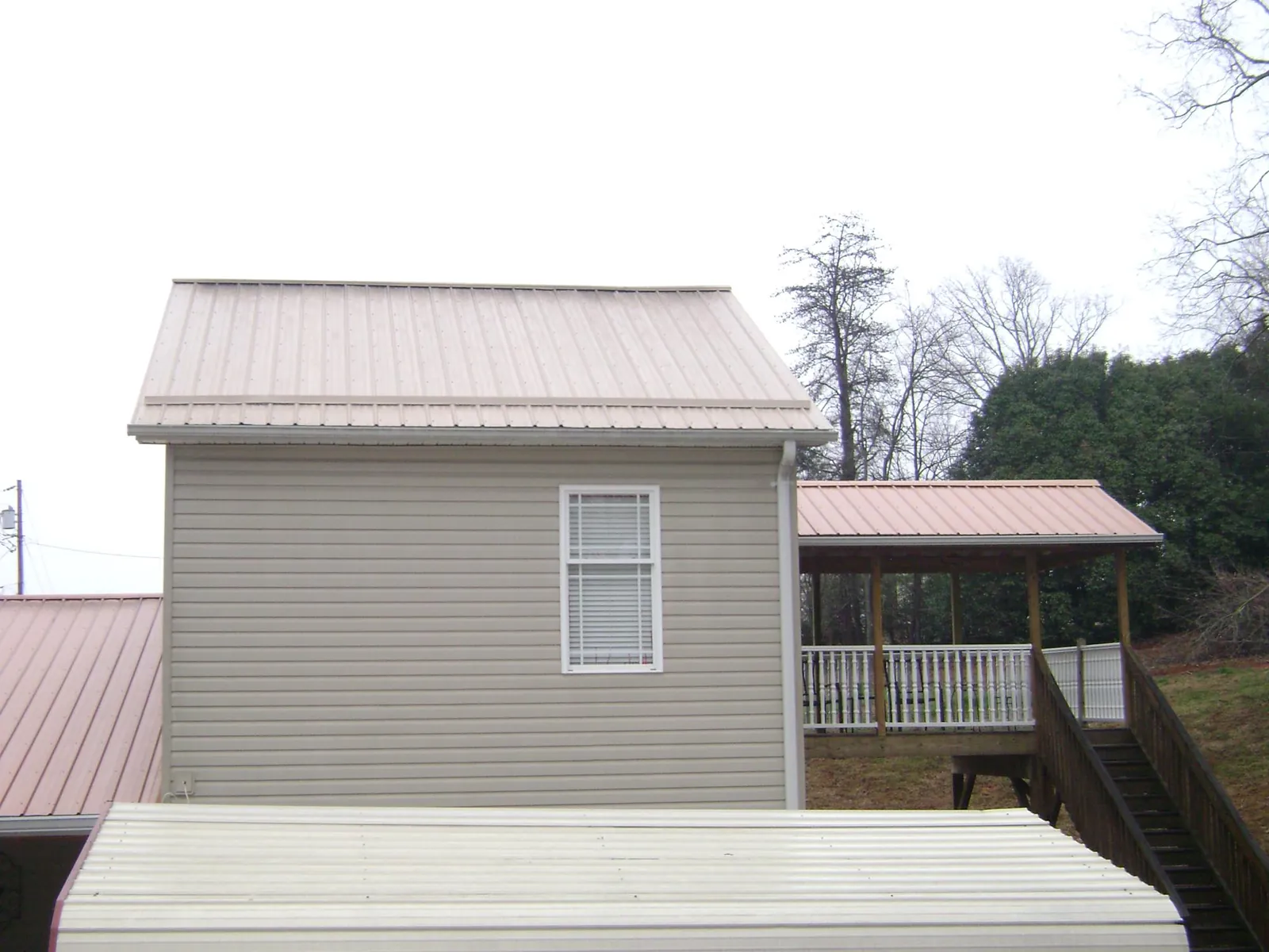 Tan metal roofs on a two story addition and attached porch, from a Roof Replacement job in Ruckersville