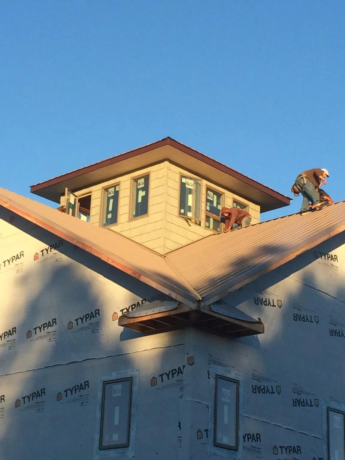 Roofers working around a rooftop cupola on a new metal roof at sunset — Roof Waterproofing in Ruckersville by Roofing Brothers